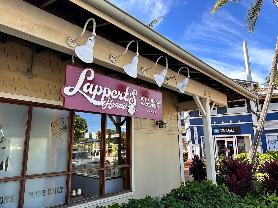 A maroon Lappert's Hawaii ice cream and coffee sign hangs on a beige storefront beneath white lamps.