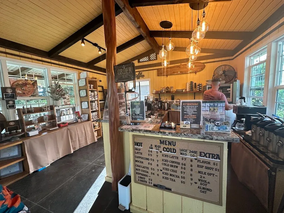 Cafe interior with a service counter, hanging bulbs, an order sign, and a handwritten drink menu board.