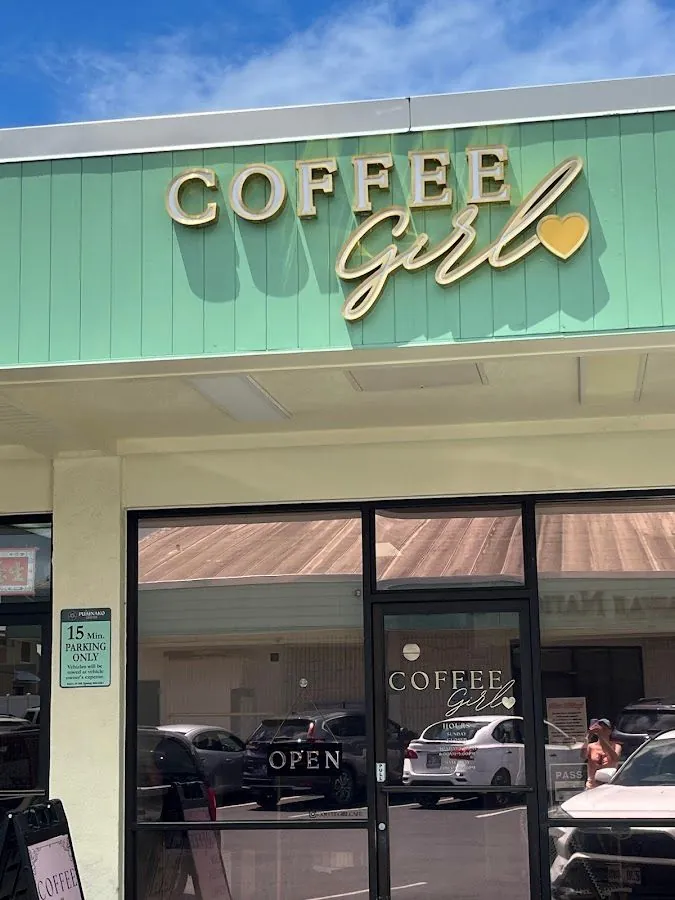 Mint-green Coffee Girl storefront with gold lettering above glass doors, an Open sign, and a 15-minute parking sign.