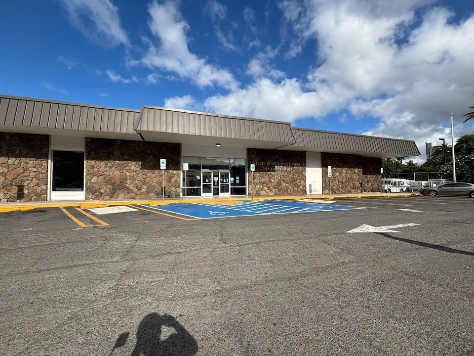 Exterior of the United States Post Office Waikiki Station in Honolulu, with accessible parking in front.