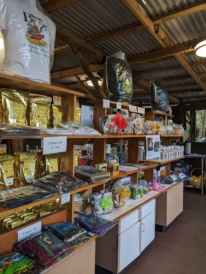 Open-air shop interior with wooden shelves of foil bags, folded shirts, gift baskets, and t-shirt price cards.