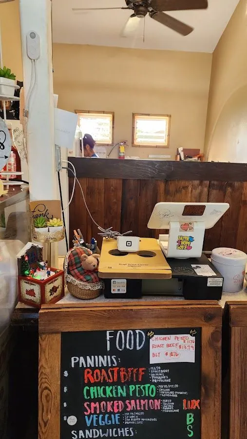 Service counter with a chalkboard food menu, a card reader, and a person behind the wood partition.