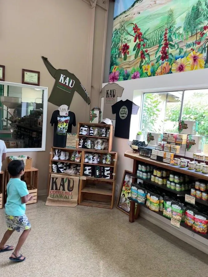 A person walks past printed shirts, packaged goods, and jars beneath a coffee-farm mural.