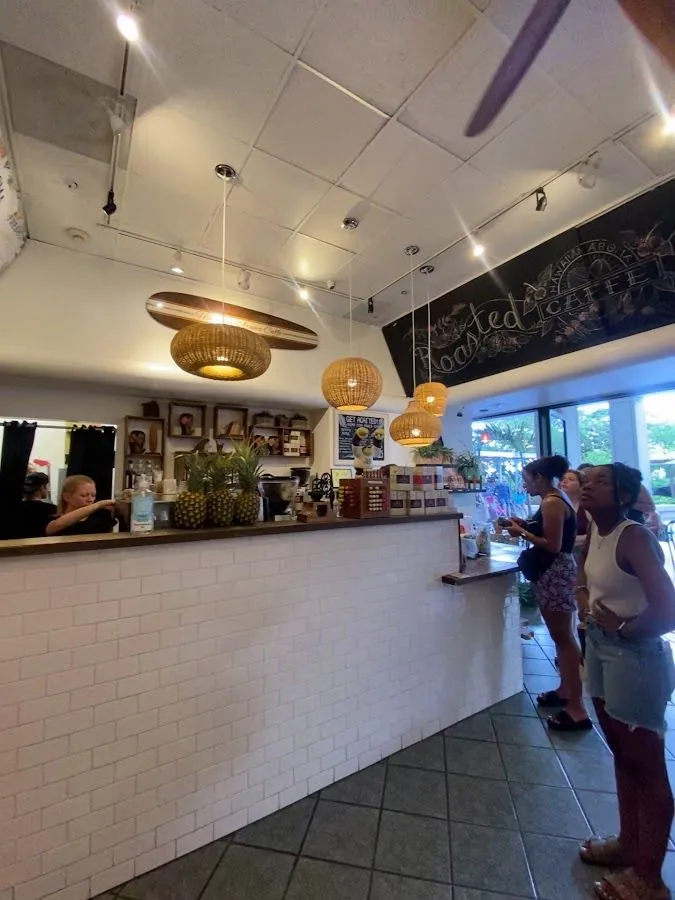 Woven pendant lights hang above a white-tile cafe counter, with staff working and customers waiting.