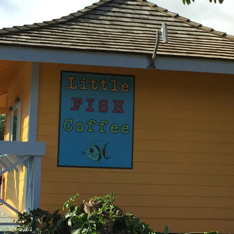 Yellow building exterior with a painted Little FISH Coffee sign and a cartoon fish.