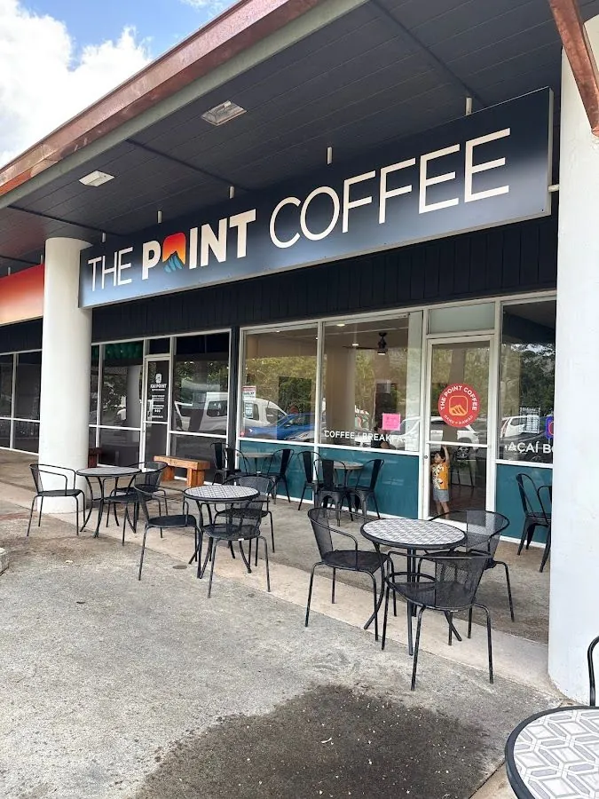 Outdoor metal tables and chairs sit under a covered walkway in front of a shop signed The Point Coffee.
