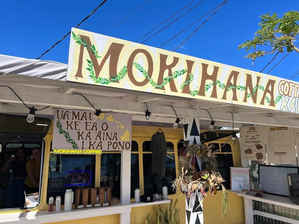Yellow Mokihana Coffee shop front under a large painted sign, with two people at the open service window.
