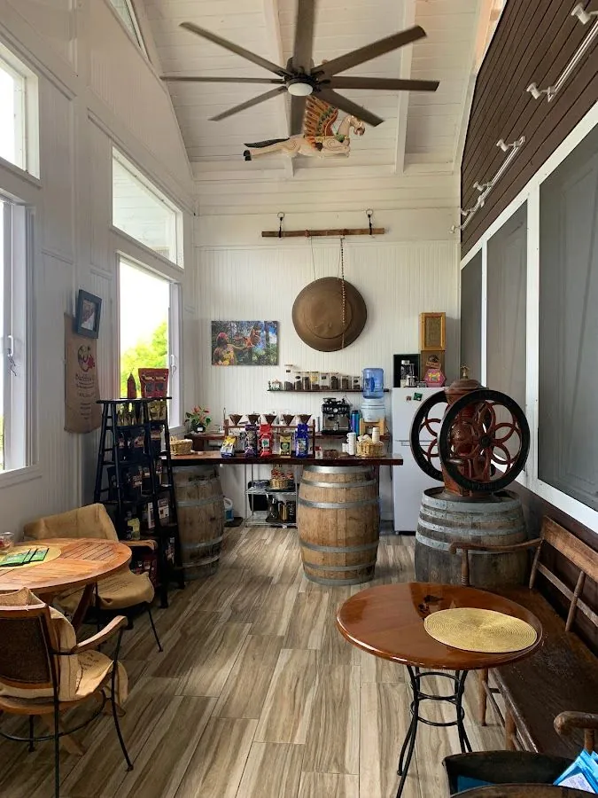 Sunlit white room with wood tables, barrel counters, a large mill wheel, and a ceiling fan.