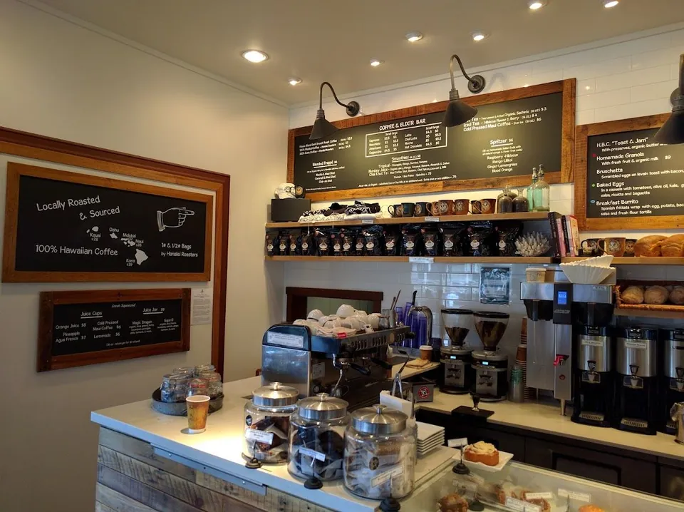 Coffee bar interior with chalkboard menus, espresso machine, grinders, and bagged coffee on shelves.