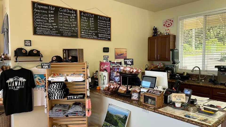 Cafe counter and merchandise wall with two chalkboard drink menus, shirts, hats, and packaged coffee.
