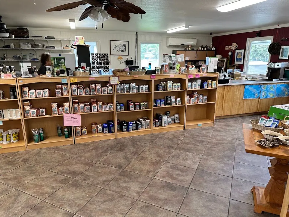 Shop interior with wooden shelves of bagged coffee, a tiled floor, and a worker behind the left counter.