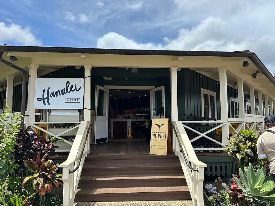 Green market building entrance with stairs, a Hanalei Market banner, and an Outpost Coffee Roast sign.