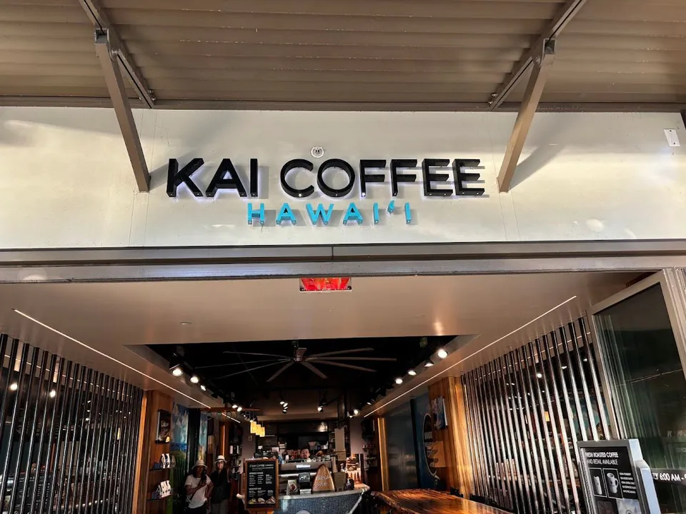 Storefront sign reading Kai Coffee Hawai'i above an open shop entrance.