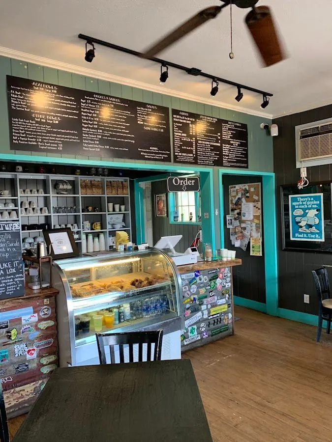 Cafe counter with a glass pastry case, sticker-covered front, menu boards, and an Order sign.