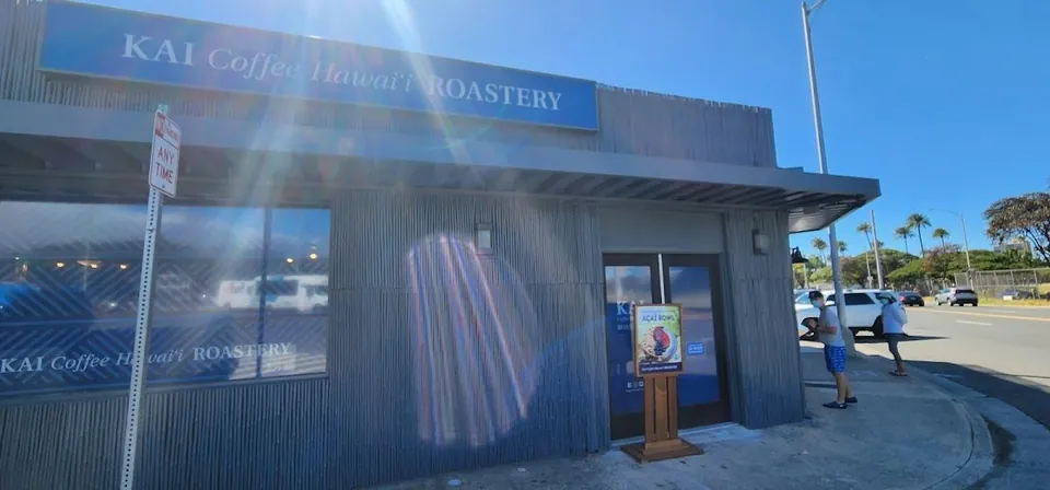KAI Coffee Hawai'i Roastery storefront with a blue sign and two people near the door.