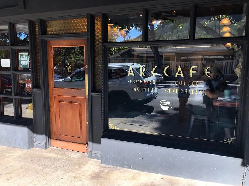 Black-framed storefront of ARS Cafe with gold window lettering, a wood door, and sidewalk in front.