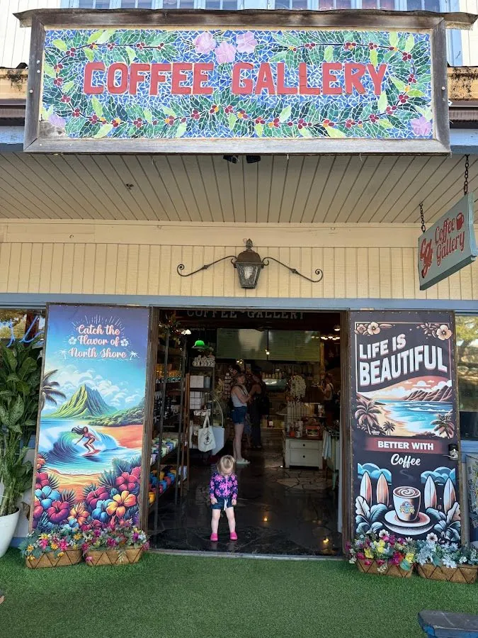 Coffee Gallery entrance under a mosaic sign, with painted doors and a person standing in the doorway.