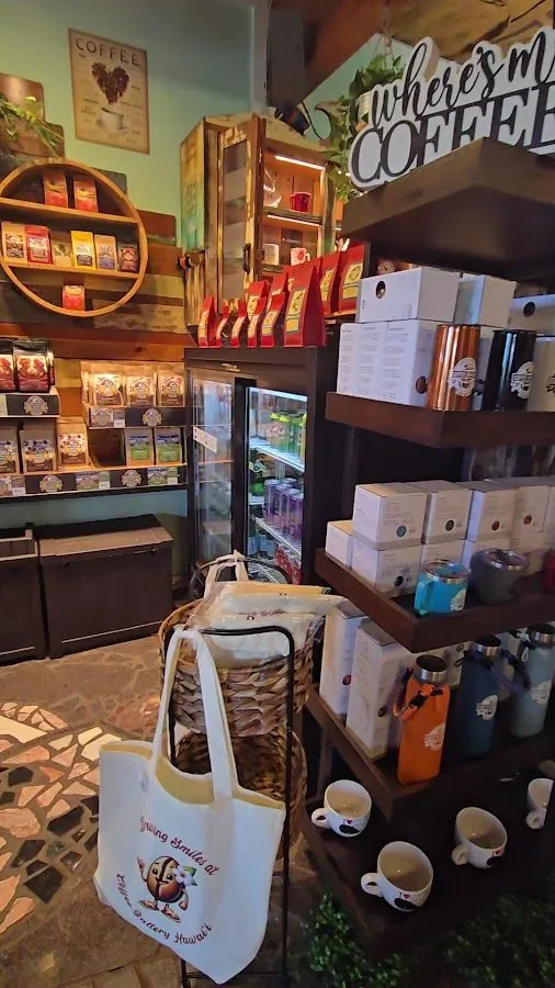 Coffee shop interior with bag shelves, a glass refrigerator, boxed goods, tumblers, mugs, and a printed tote.