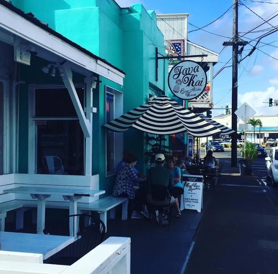 Turquoise Java Kai storefront with outdoor tables, seated customers, and a striped umbrella on a sunny street.