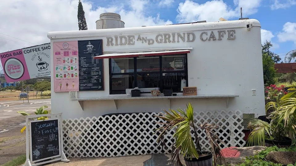 White Ride and Grind Cafe trailer outdoors, with a service window, menu boards, and a soda-bar banner.