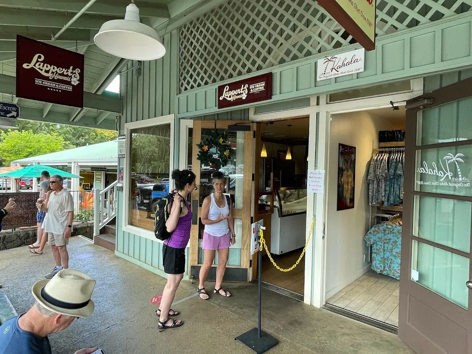 People stand at the open entrance of a shop signed Lappert's Ice Cream & Coffee and Kahala, on a covered walkway.