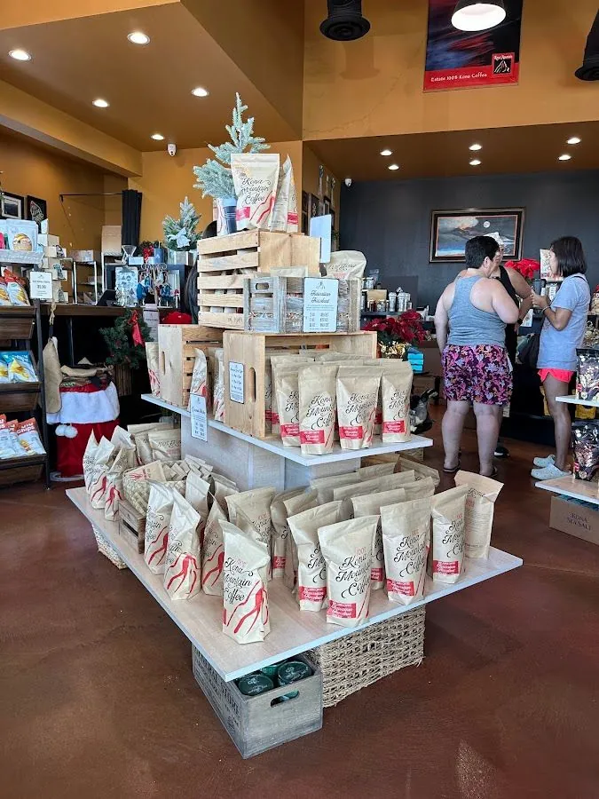 Shop interior with Kona Mountain Coffee bags on wooden displays and people standing near the back.