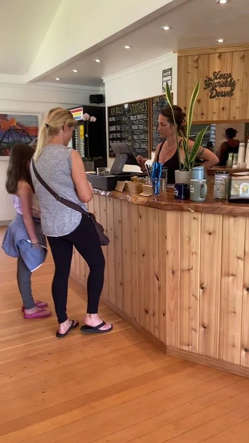 Two people stand at a curved wood counter facing a person who serves from behind it.