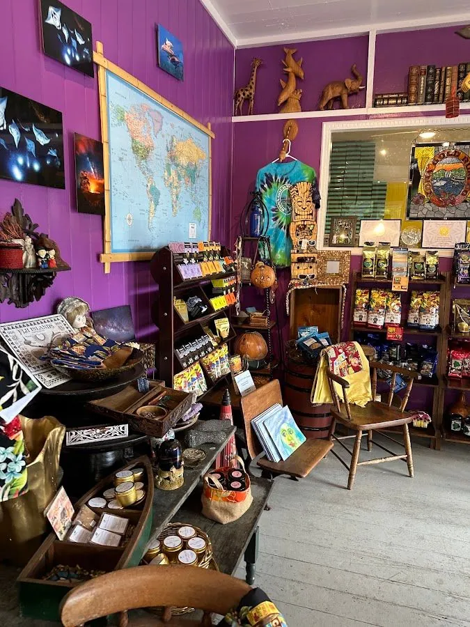 Purple shop interior with a world map, carved wooden animals, souvenir displays, and packaged bags on shelves.