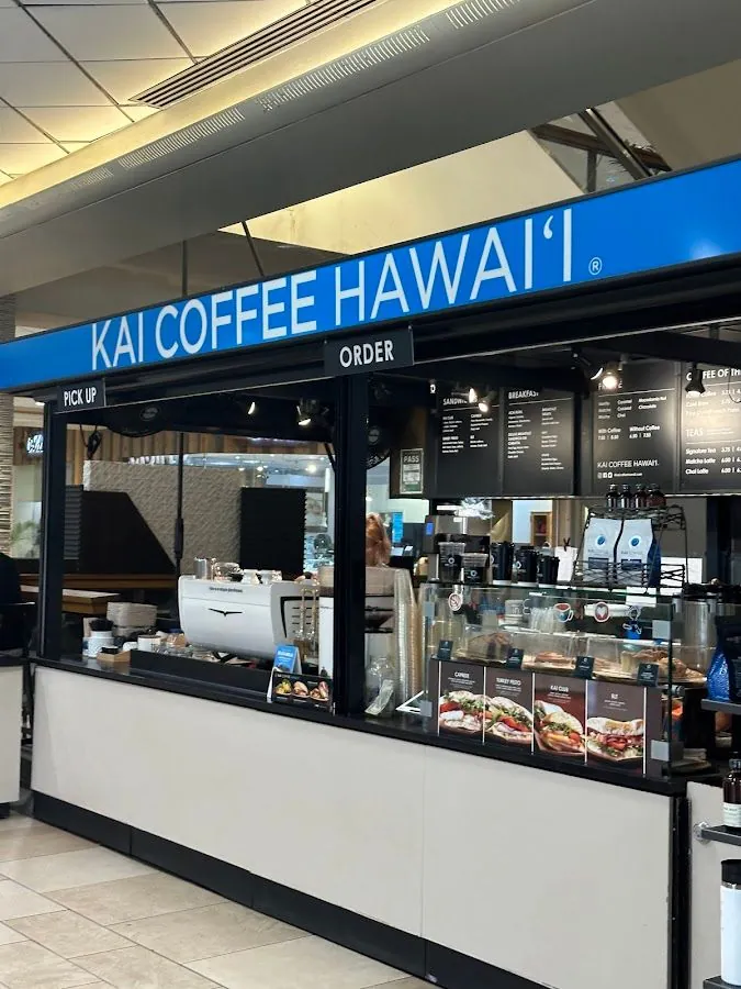 Kai Coffee Hawai'i counter with pickup and order signs, an espresso machine, menu boards, and a food display case.